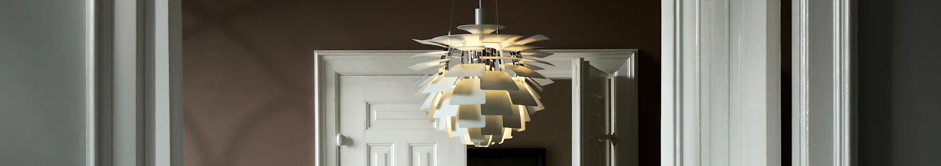 A white, sculptural pendant light with multiple layers illuminates a doorway.
