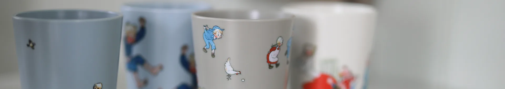 Four mugs in a row, the two in the middle with illustrations of a boy, a woman, and a chicken.