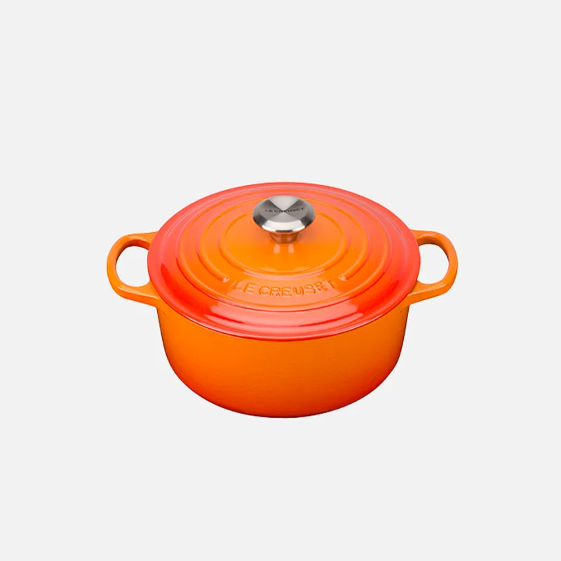 Orange and red gradient Le Creuset Dutch oven with a silver knob on its lid, against a white background.