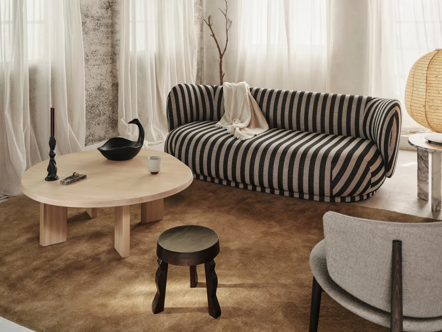 Cozy living room with a black and off-white striped sofa, light wood coffee table, and rustic wooden beamed ceiling.