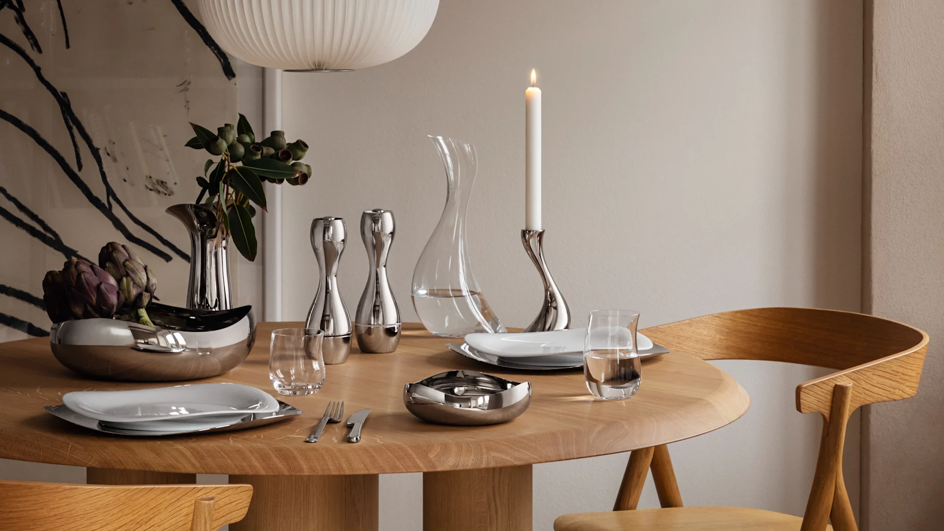 A modern dining table set with silver tableware, including two bowls, salt and pepper shakers, a vase, and a lit candle.
