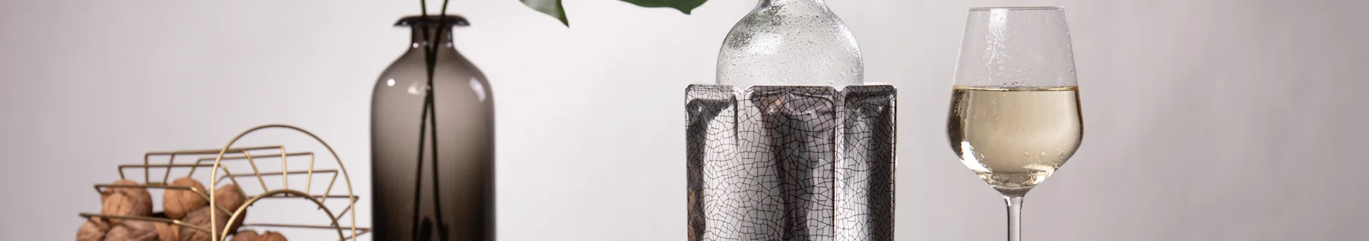 Close-up of a table with a gold basket of walnuts, a dark vase, a chilled bottle in a cooler, and a champagne flute.