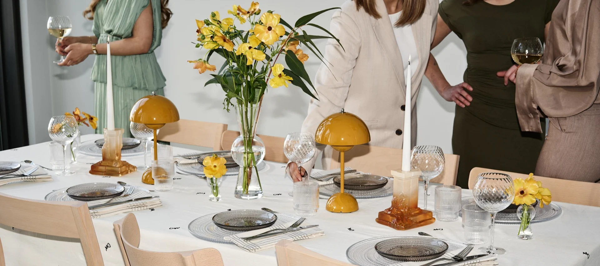 How to throw a party with a real party atmosphere, here you see a set table with yellow accents and guests mingling around the table. 