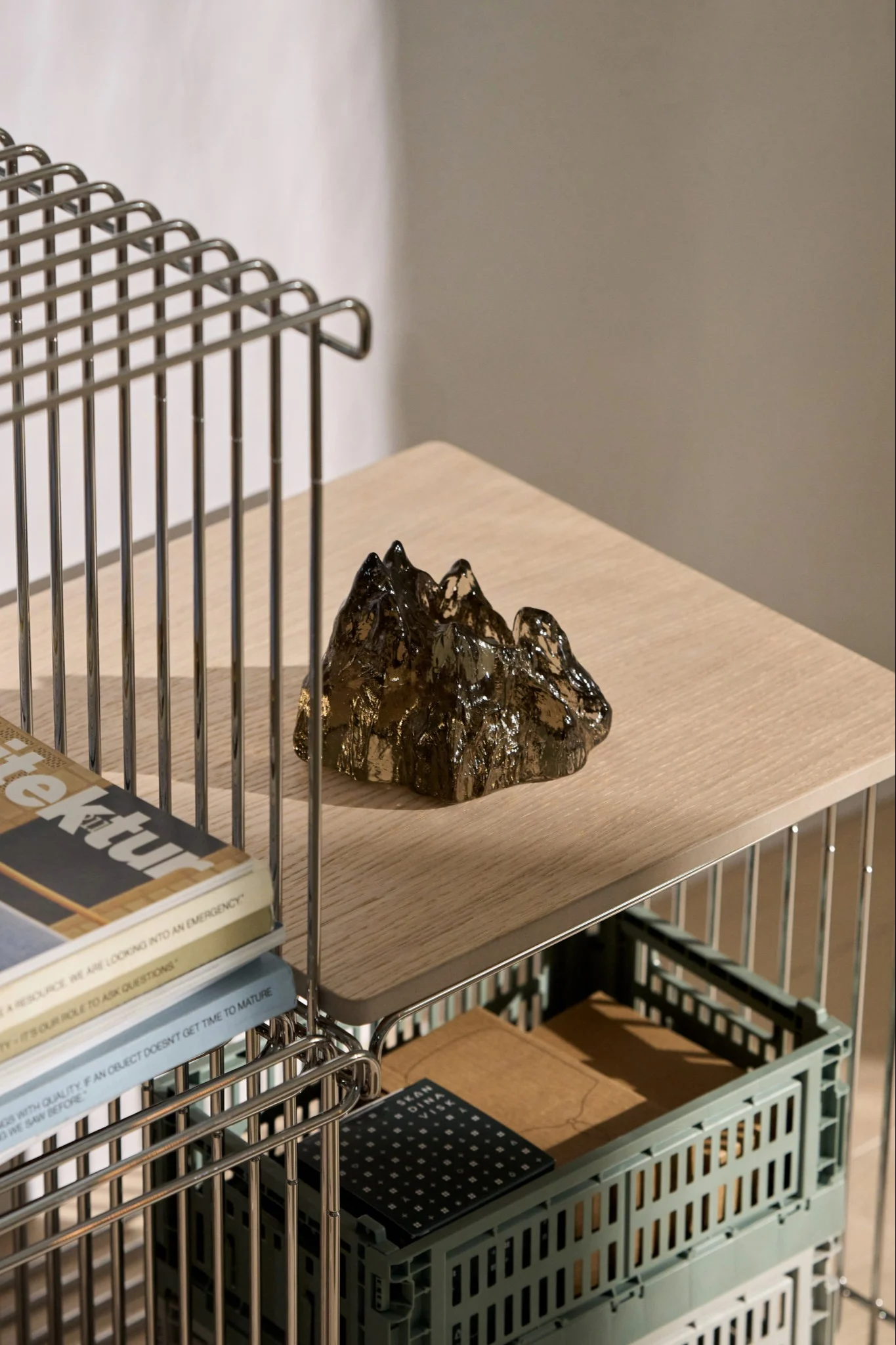 A handcrafted glass candle holder on a steel table with a wooden top.