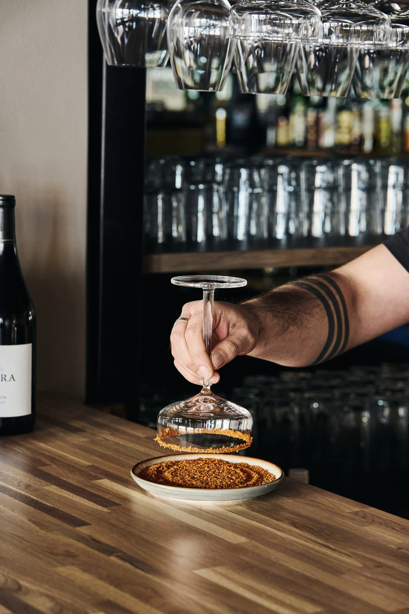 A hand dips the rim of a margarita cocktail glass in the salt mixture to add extra flavour to the drink. 
