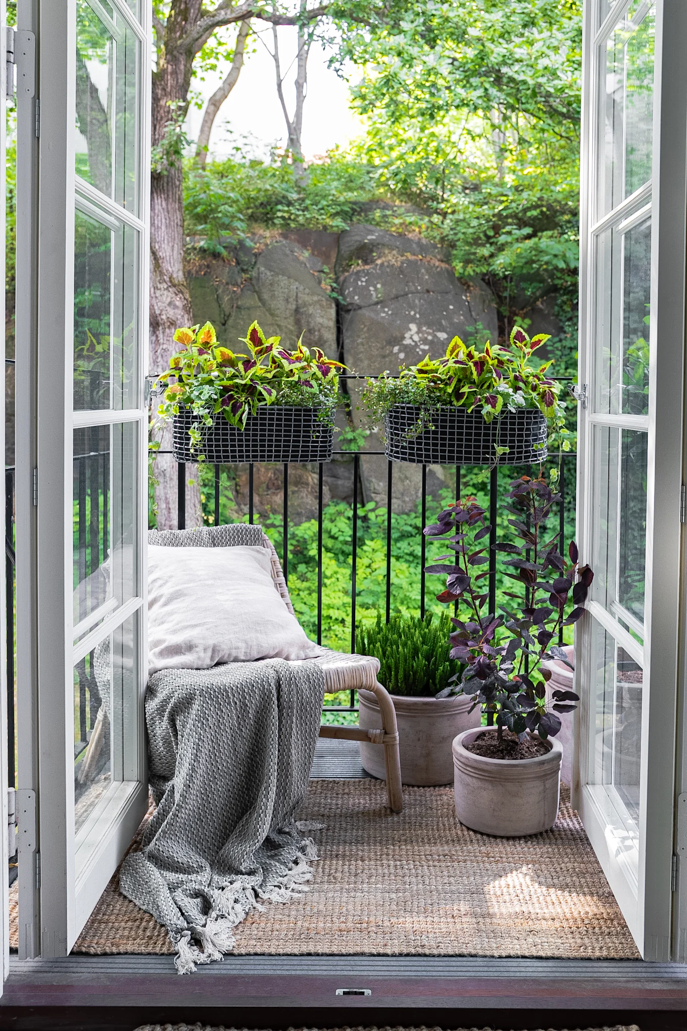 A small, cosily furnished balcony with an armchair and several plants, including in the Korbo balcony box.
