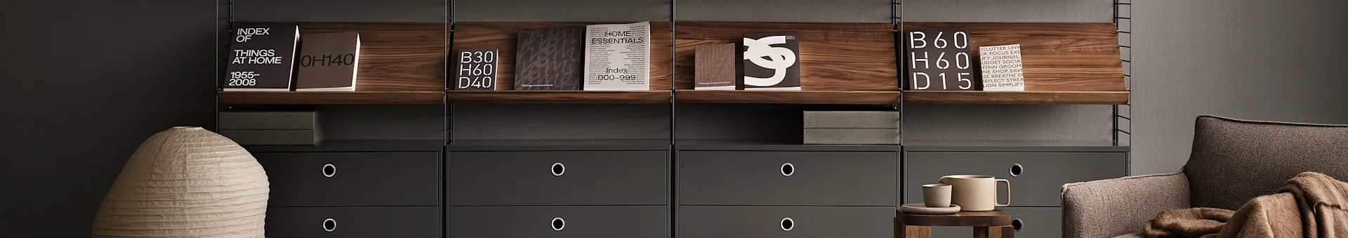 Modern shelving unit with dark wood shelves, grey drawers, books, a light-colored vase, a brown armchair, and ceramic accessories.