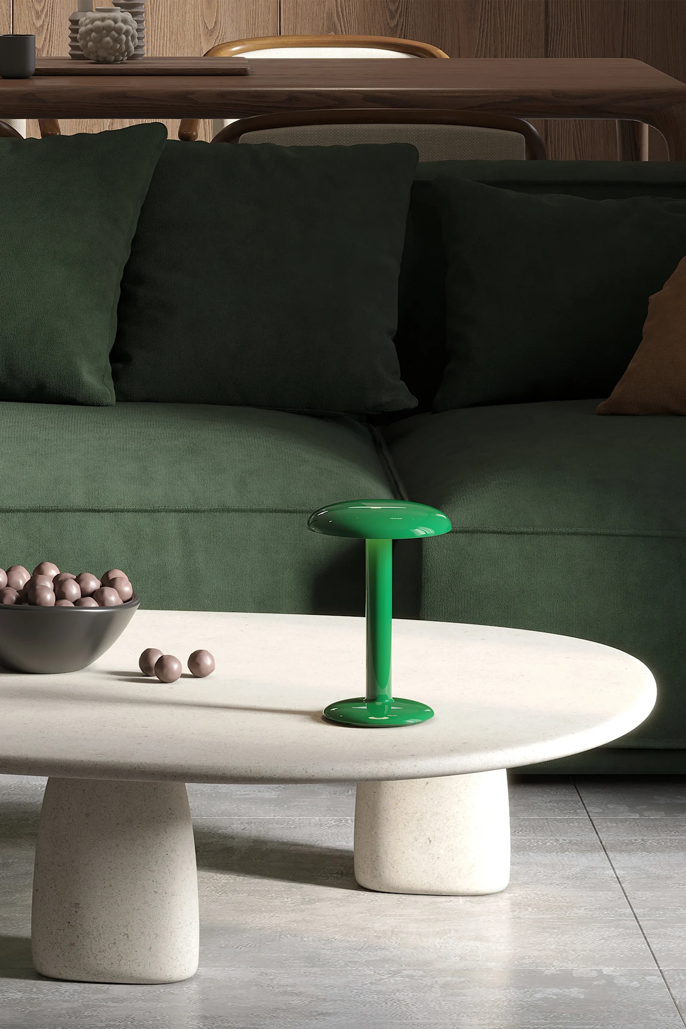A green mushroom-shaped table lamp on an oval coffee table, with a bowl of candies and a dark green sofa.