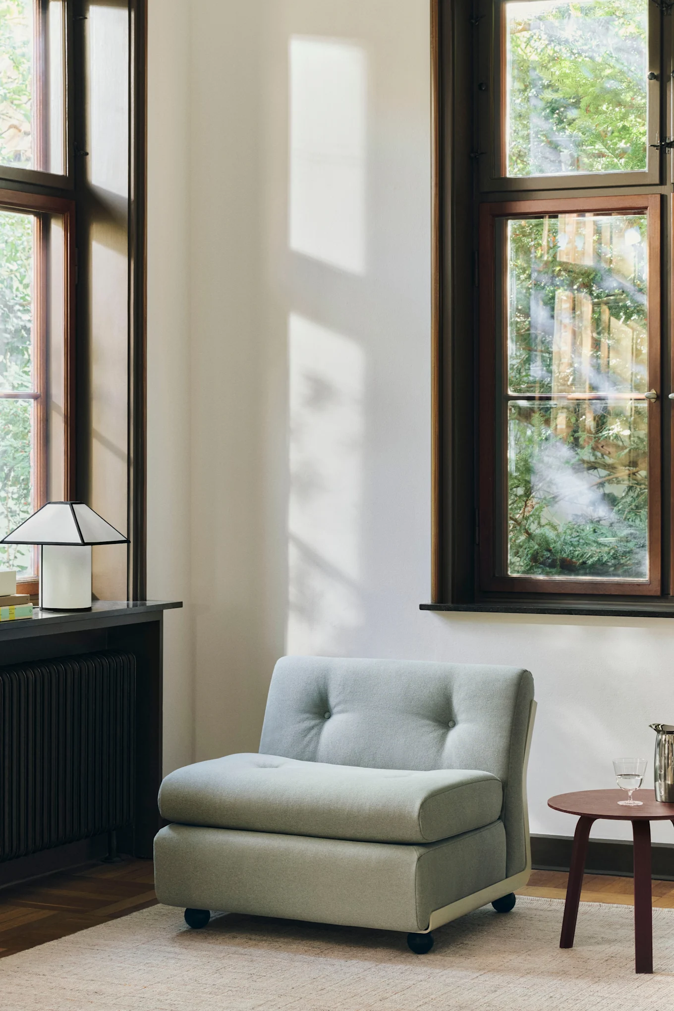 A round sofa module placed in a room with large windows, showcasing the interior design trends of 2026.