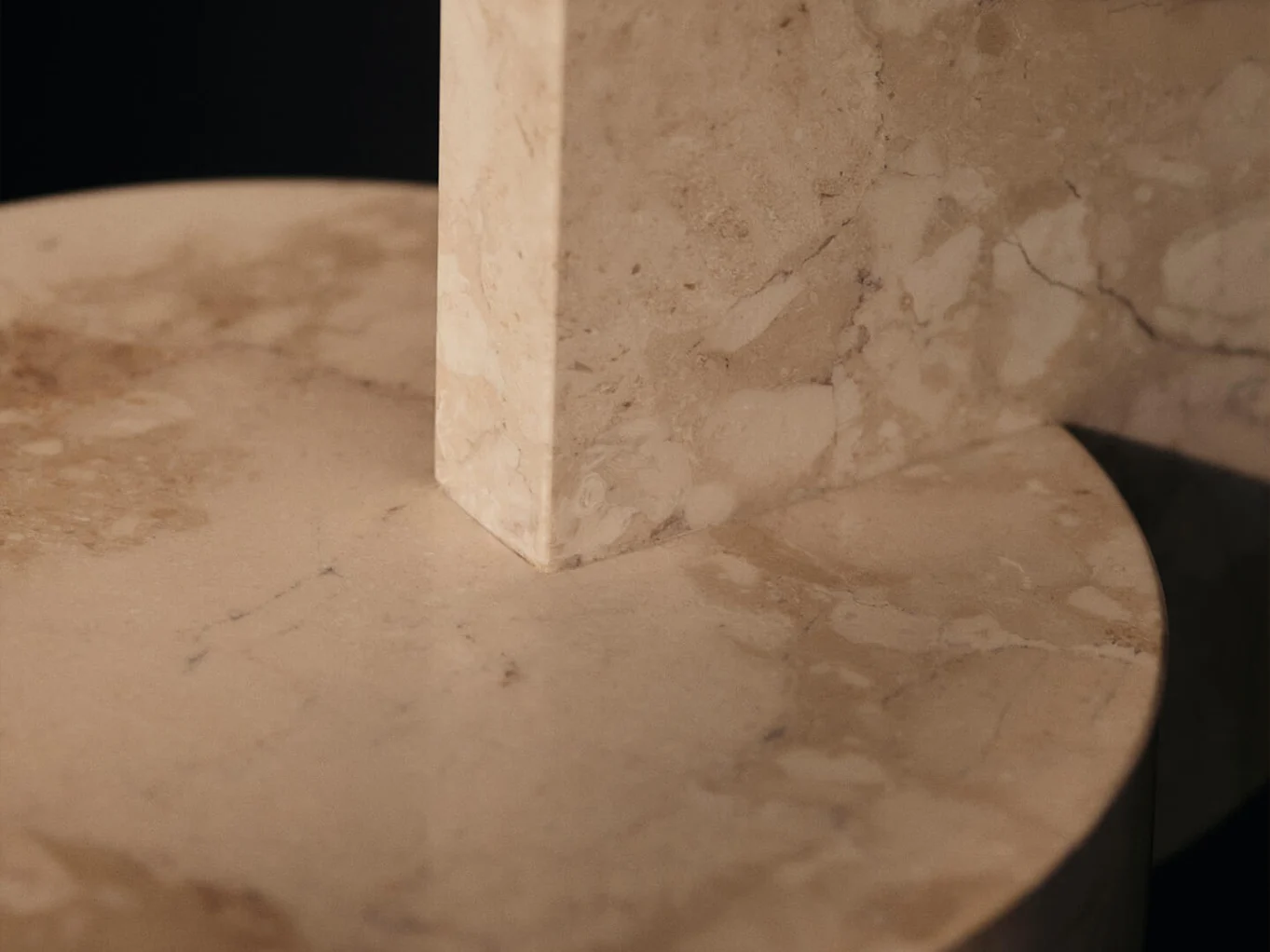 Close-up of a rectangular marble block resting on a round marble surface, showing natural veining.